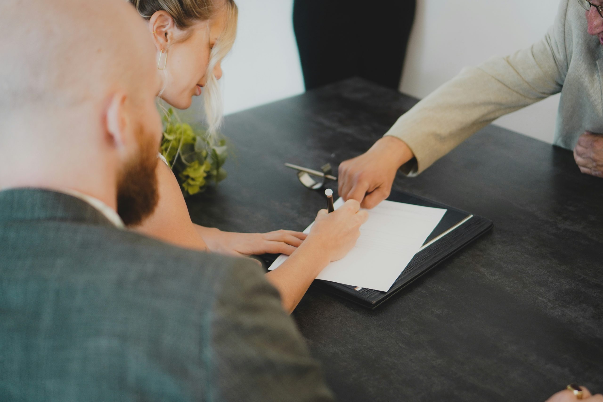 Couple signing paperwork with a real estate agent, representing how to choose a Maryland real estate agent